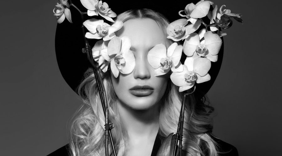 portrait-of-a-blonde-woman-in-a-large-round-black-hat-an-orchid-flower-in-her-hands.jpg